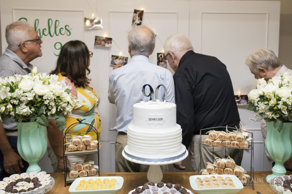 convidados olhando o varal de fotos da festa de 90 anos