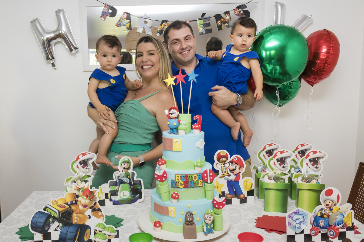 Familia em frente a mesa do bolo decorada com o tema Mario Bros