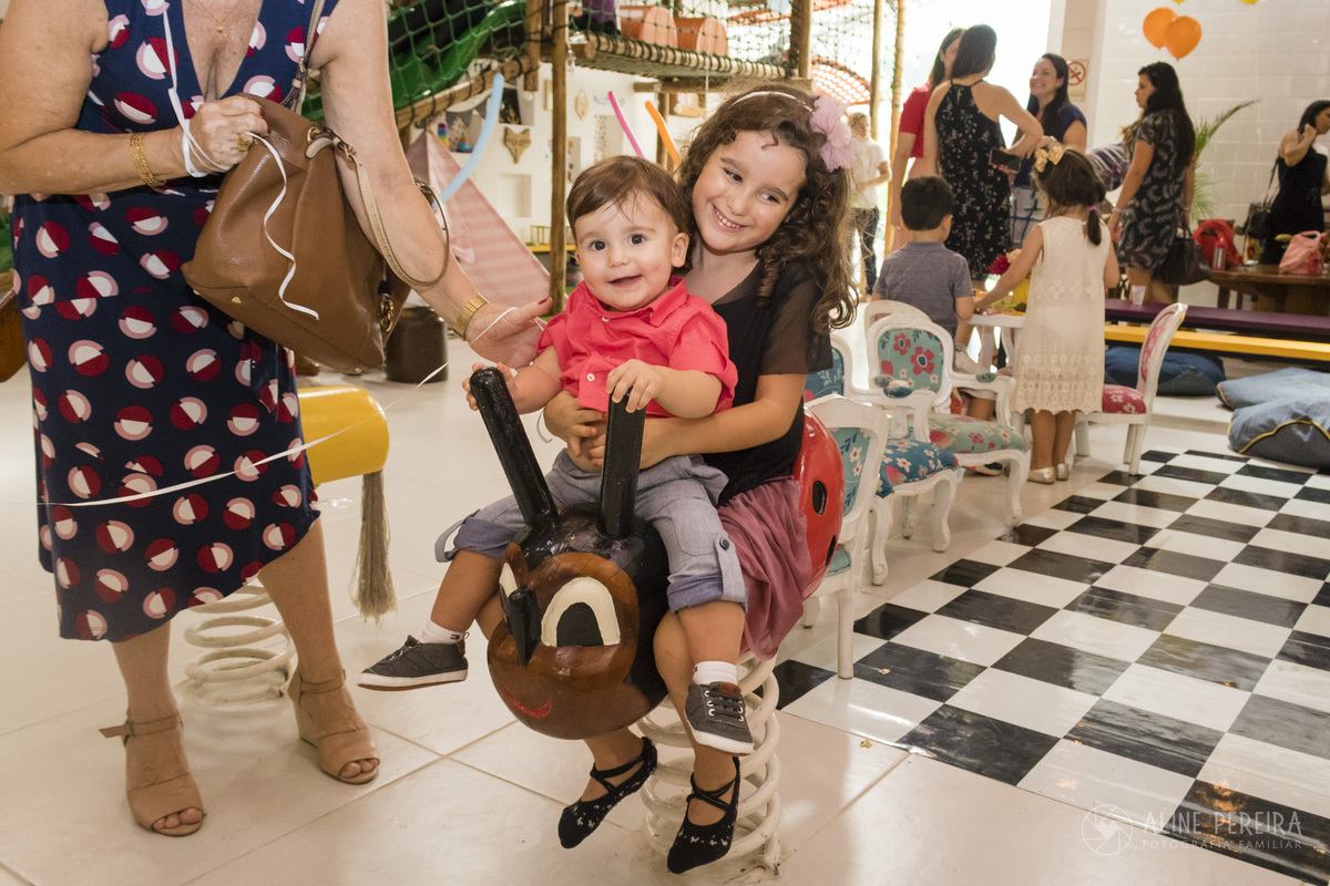 irmãos se balançando no brinquedo da casa de festas Quintal