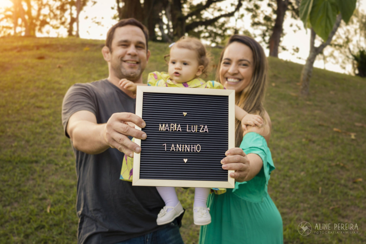 Casal segurando a placa de comemoração ao primeiro ano da filha