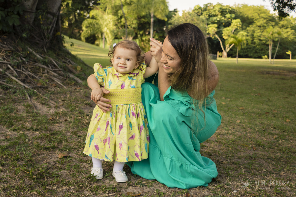 mãe olhando a filha fazer graçinha no parque