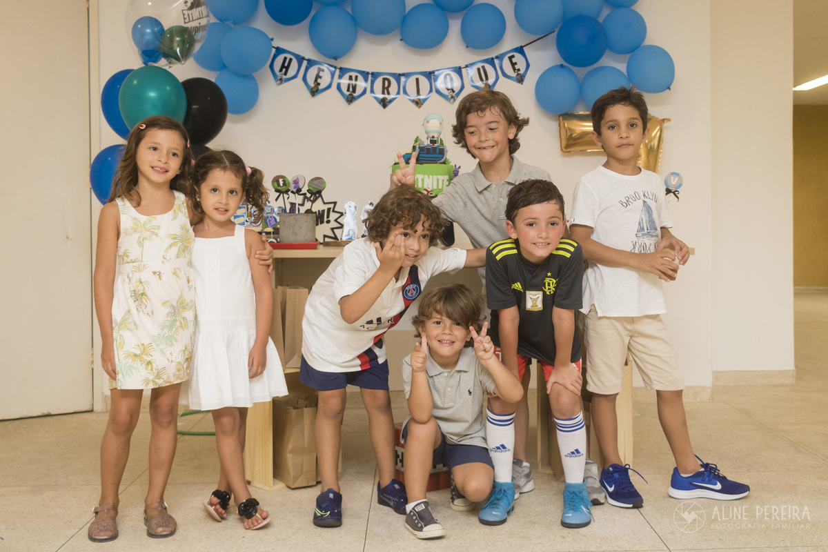 crianças juntas em frente a mesa do bolo com o tema fortnite