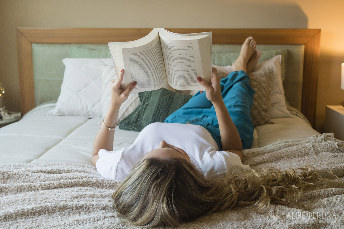 mulher deitada na cama lendo um livro