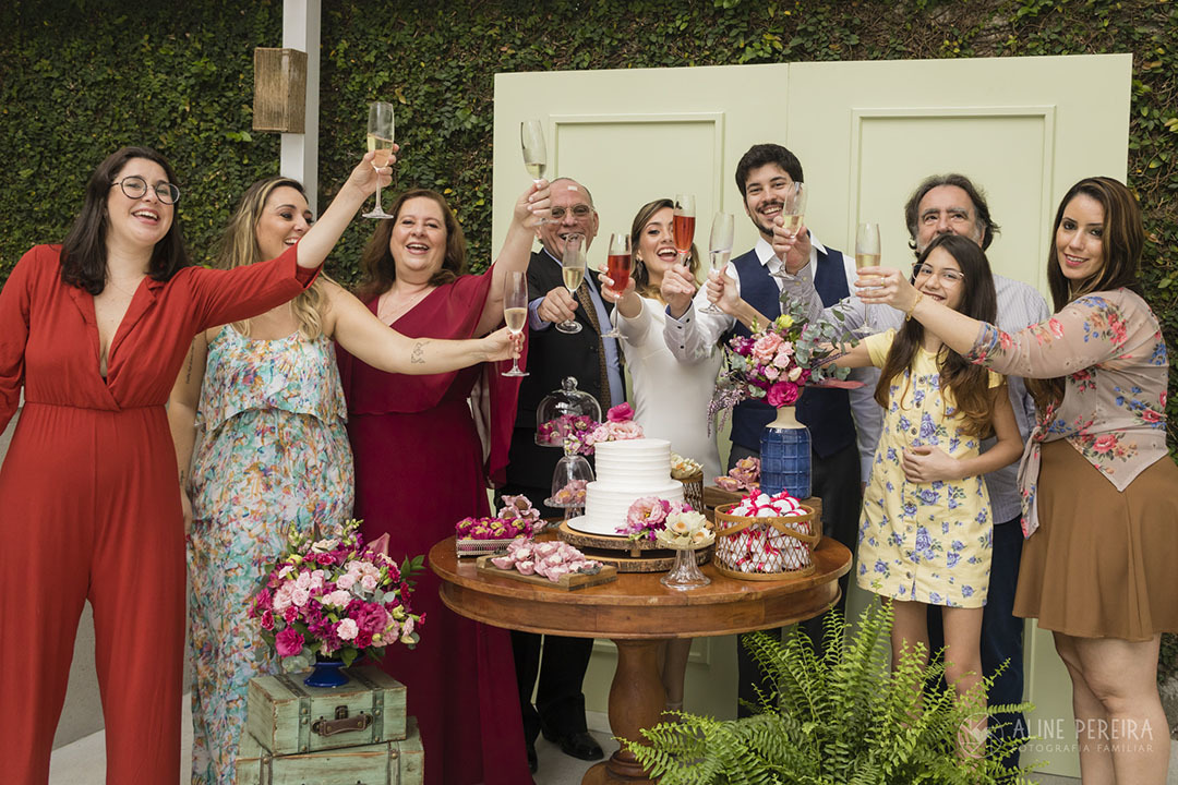 família fazendo um brunde em homenagem aos noivos na mesa do bolo