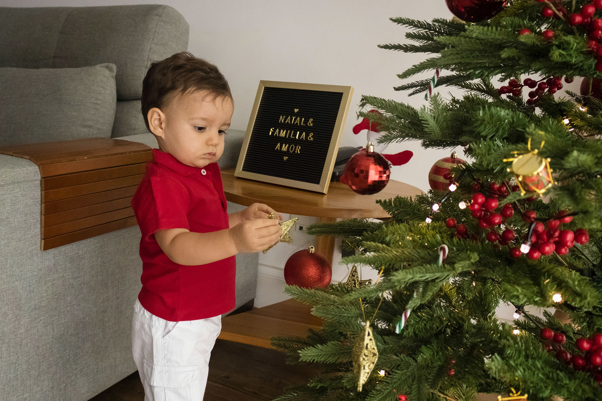 menino colocando enfeite na árvore de natal