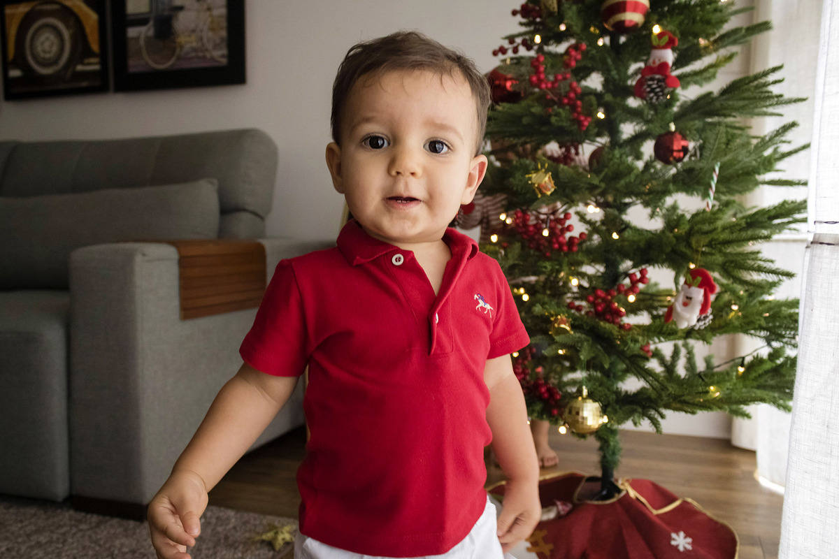 menino em frente a árvore de natal