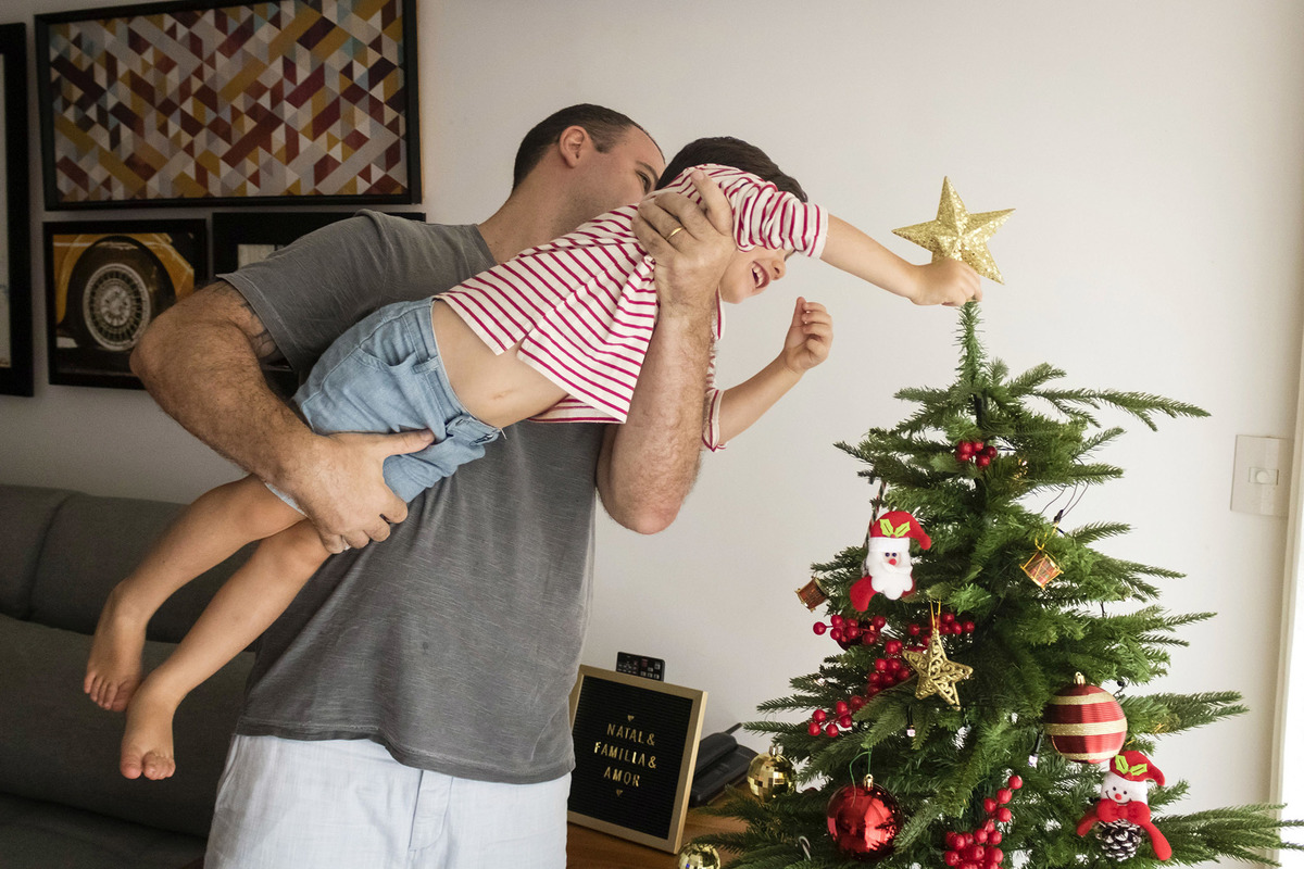 pai erguendo o filho para a colocar a estrela no topo da árvore