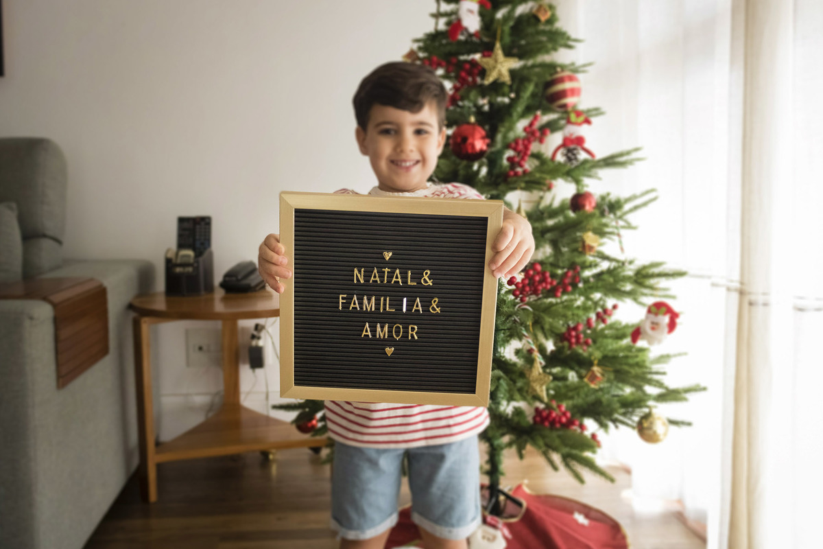 menino segurando um quadrinho com dizeres de amor, família e natal