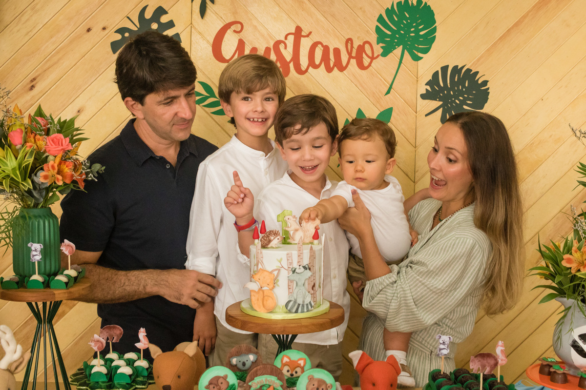 família de 5 pessoas na mesa do bolo decorada com o tema floresta