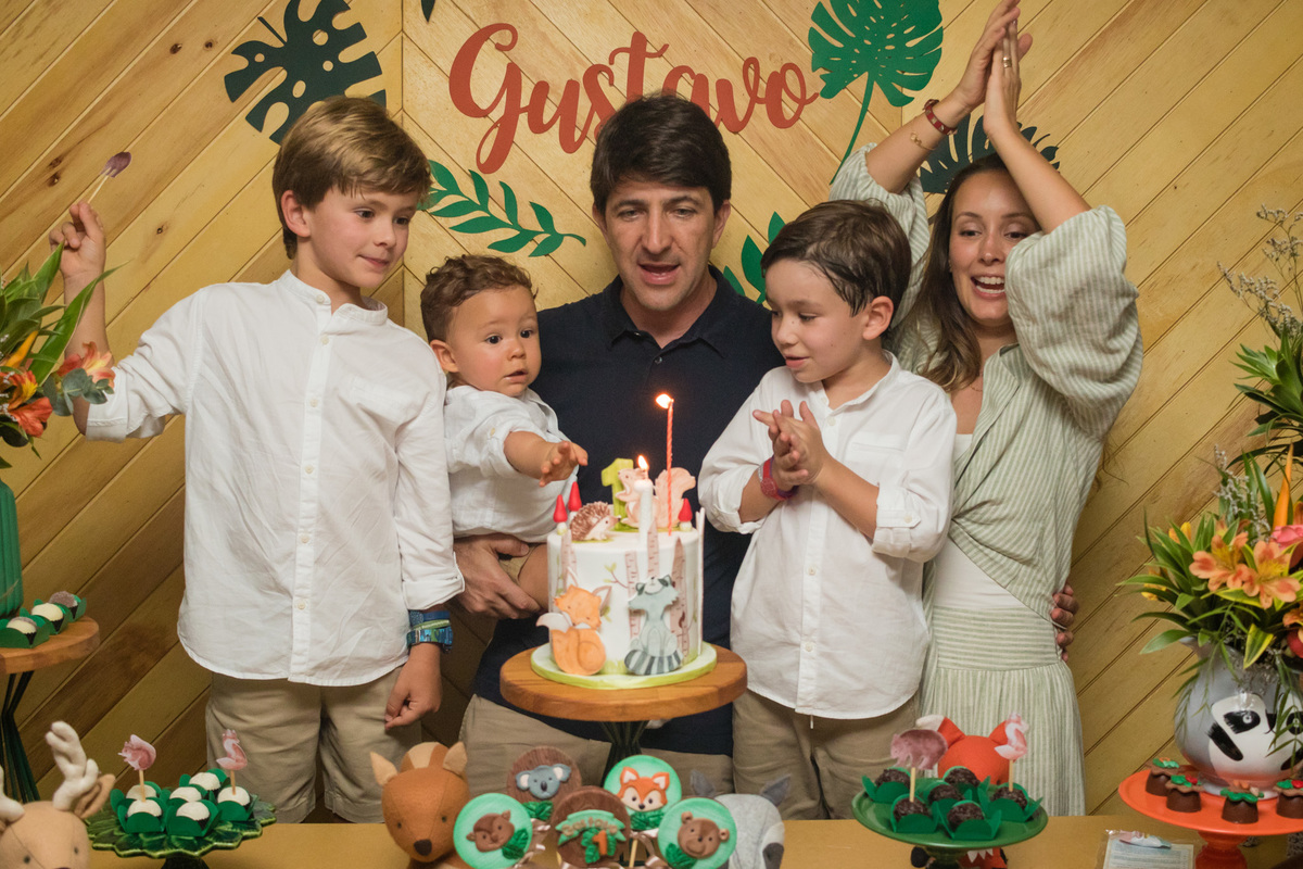 família cantando parabéns na mesa do bolo com o tema floresta