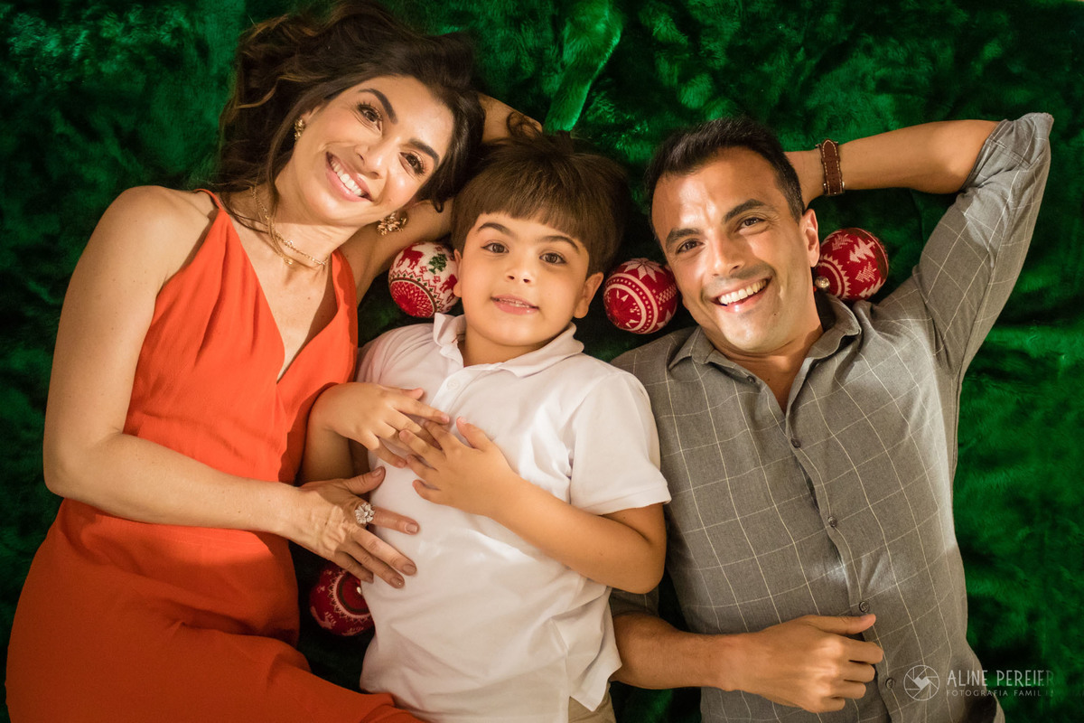 família deitada no tapete verde com luzes e bolas de natal