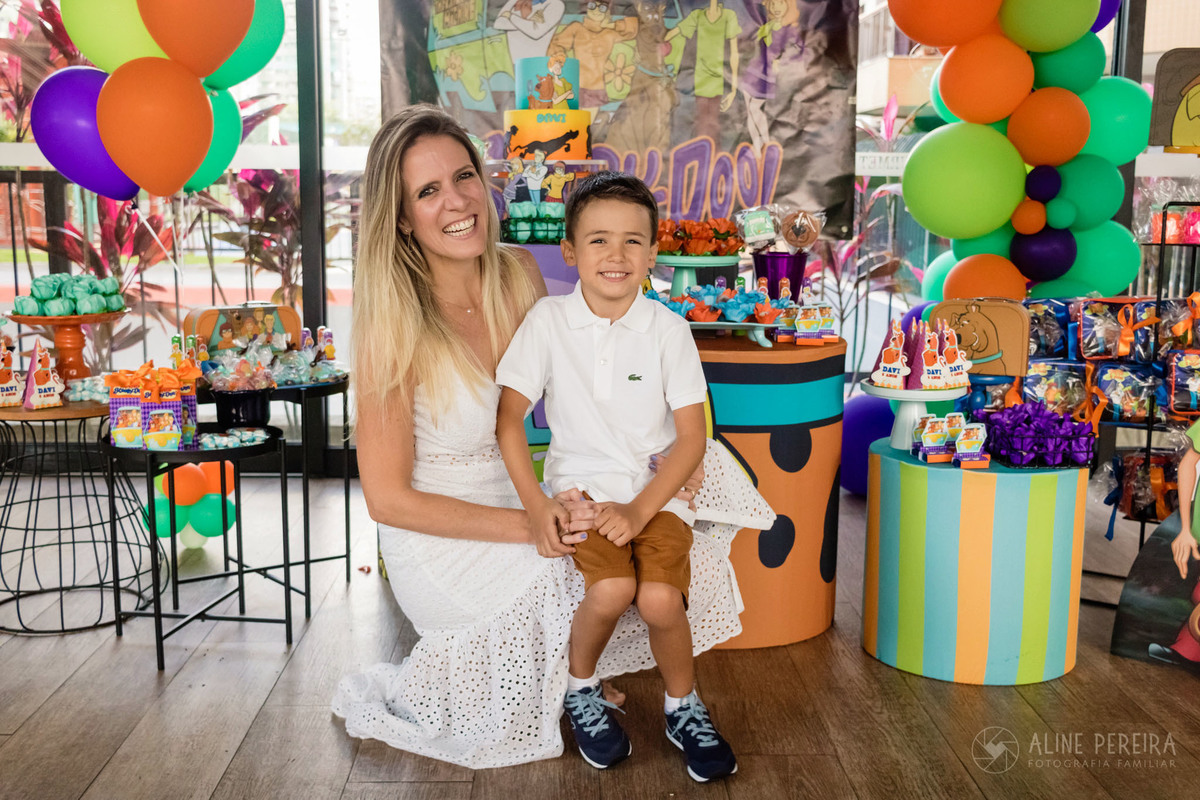 aniversariante na frente da mesa do bolo com a mãe, tema scooby-doo