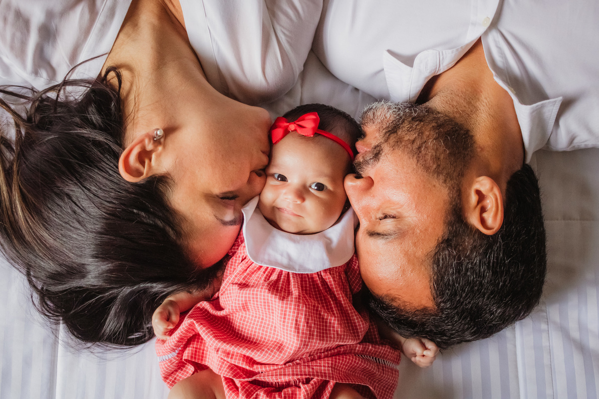 bebê entre os pais recebendo um beijinho