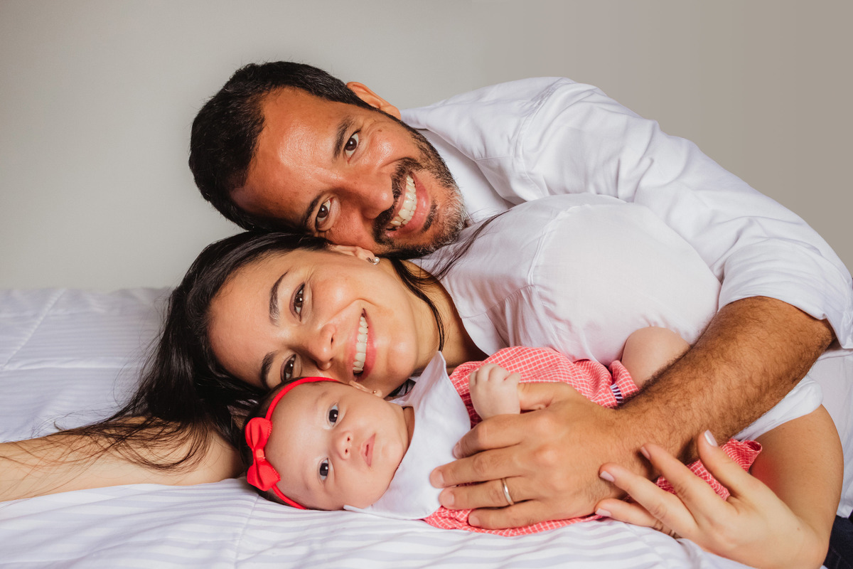 pai, mãe e filha se abraçando na cama