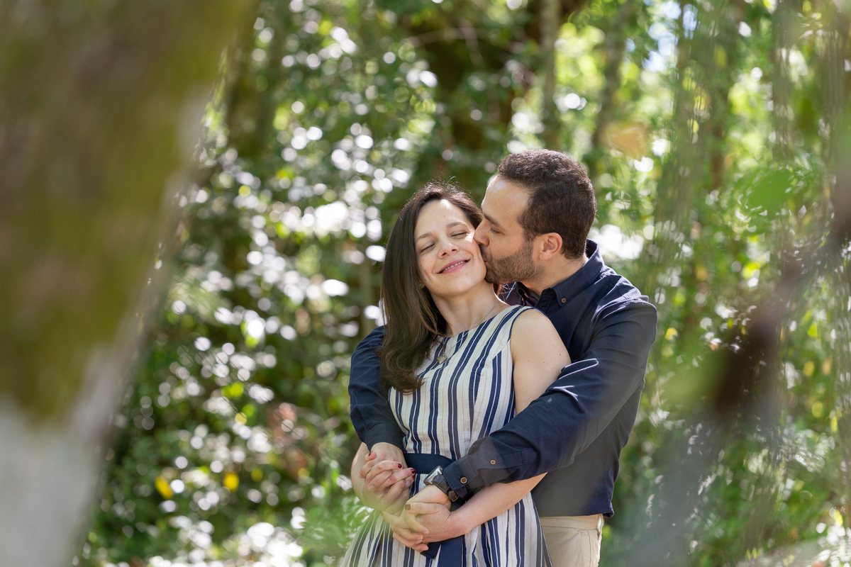 Namorados abraçados em sessão fotográfica de solteiros em jardim