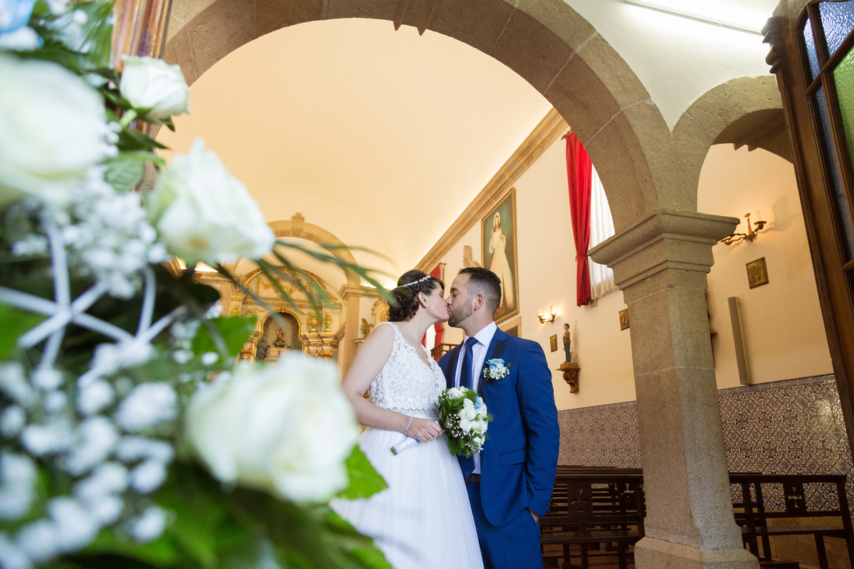 fotografia de noivos a dar beijo à saída da igreja