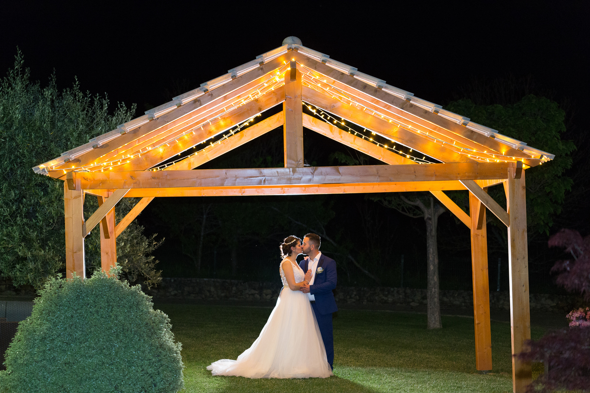 fotografia de noivos à noite debaixo da pérgola