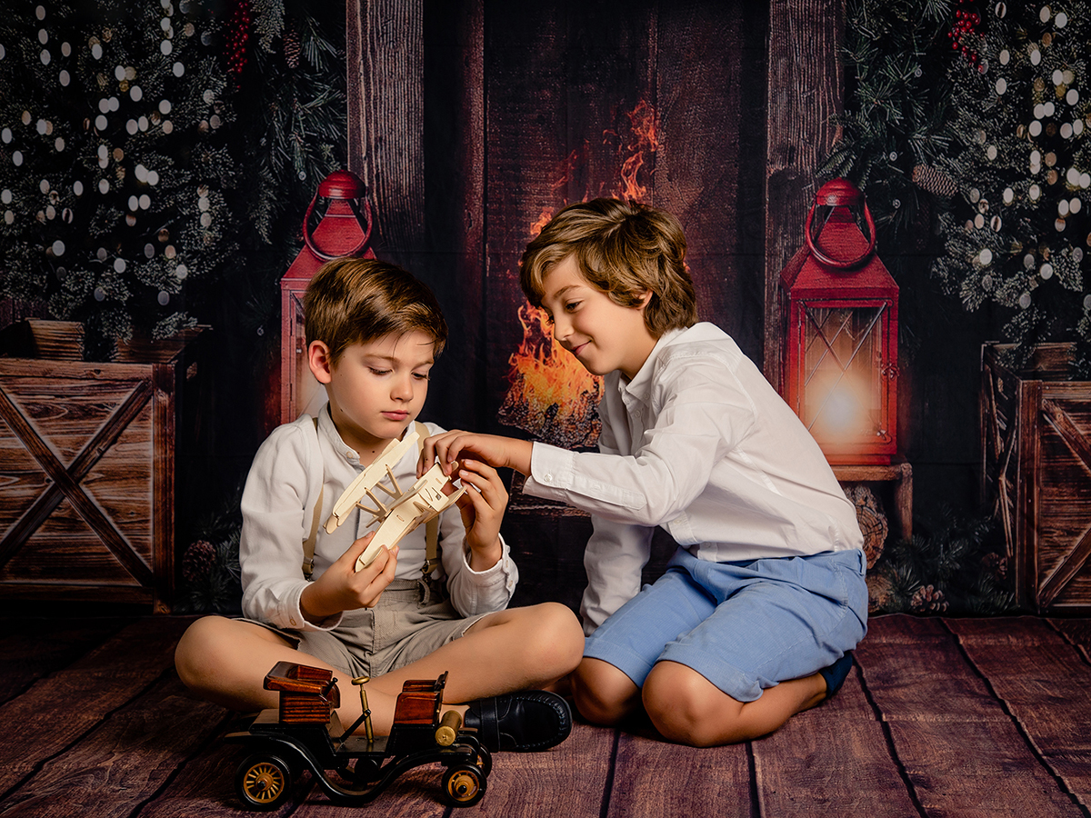 Fotografia de dois irmãos a brincar com avião de madeira no Natal