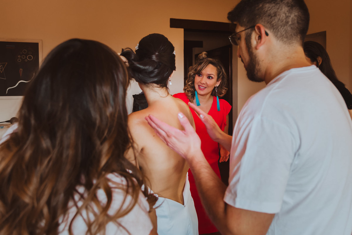 familia ayudando a la novia a colocarse el vestido de novia previo a la boda