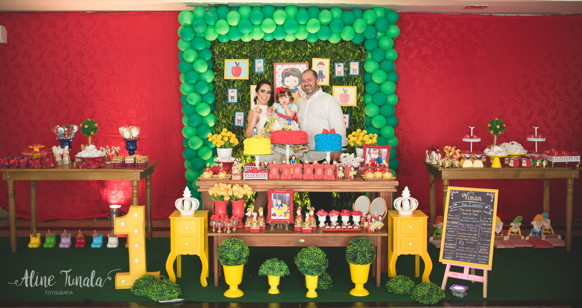 aniversário de 1 ano tema branca de neve, pais posando com a bebê na mesa