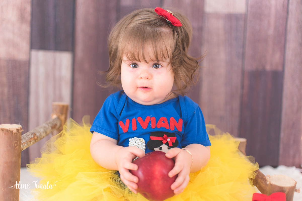 Foto temática Branca de Neve para aniversário de 1 aninho com maçãs em estúdio. Sessão infantil, ensaio infantil. 1 ano