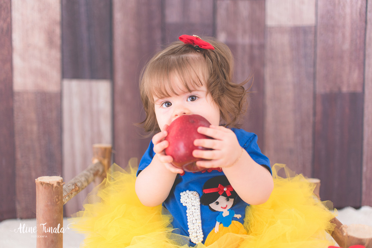 Foto temática Branca de Neve para aniversário de 1 aninho com maçãs em estúdio. Sessão infantil, ensaio infantil. 1 ano