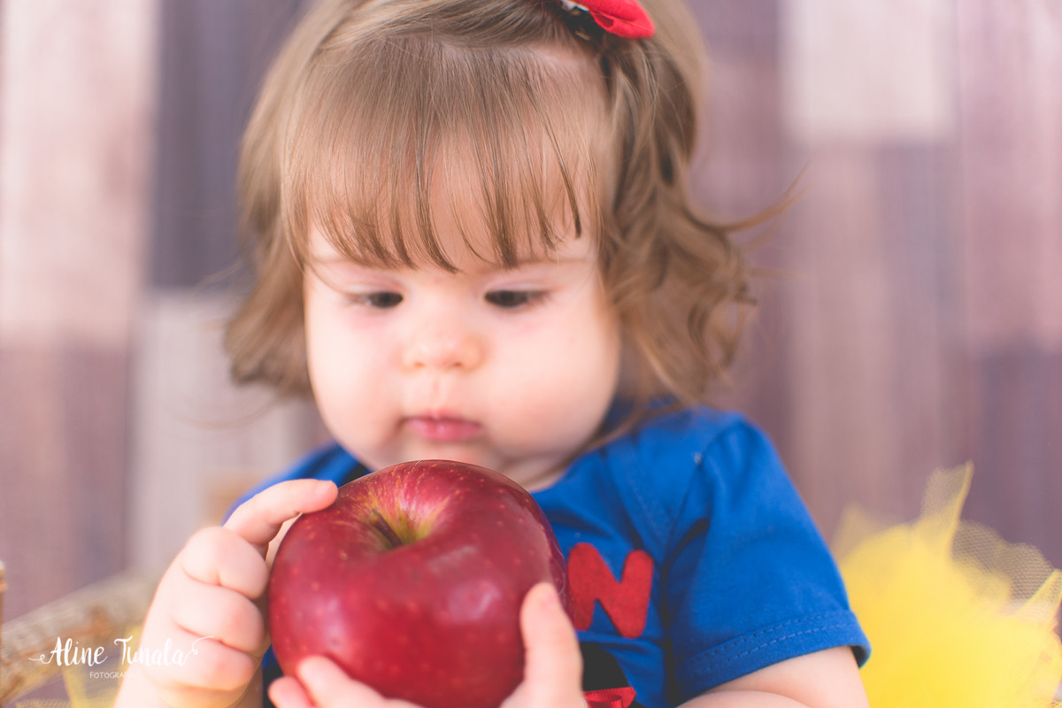 Foto temática Branca de Neve para aniversário de 1 aninho com maçãs em estúdio. Sessão infantil, ensaio infantil. 1 ano