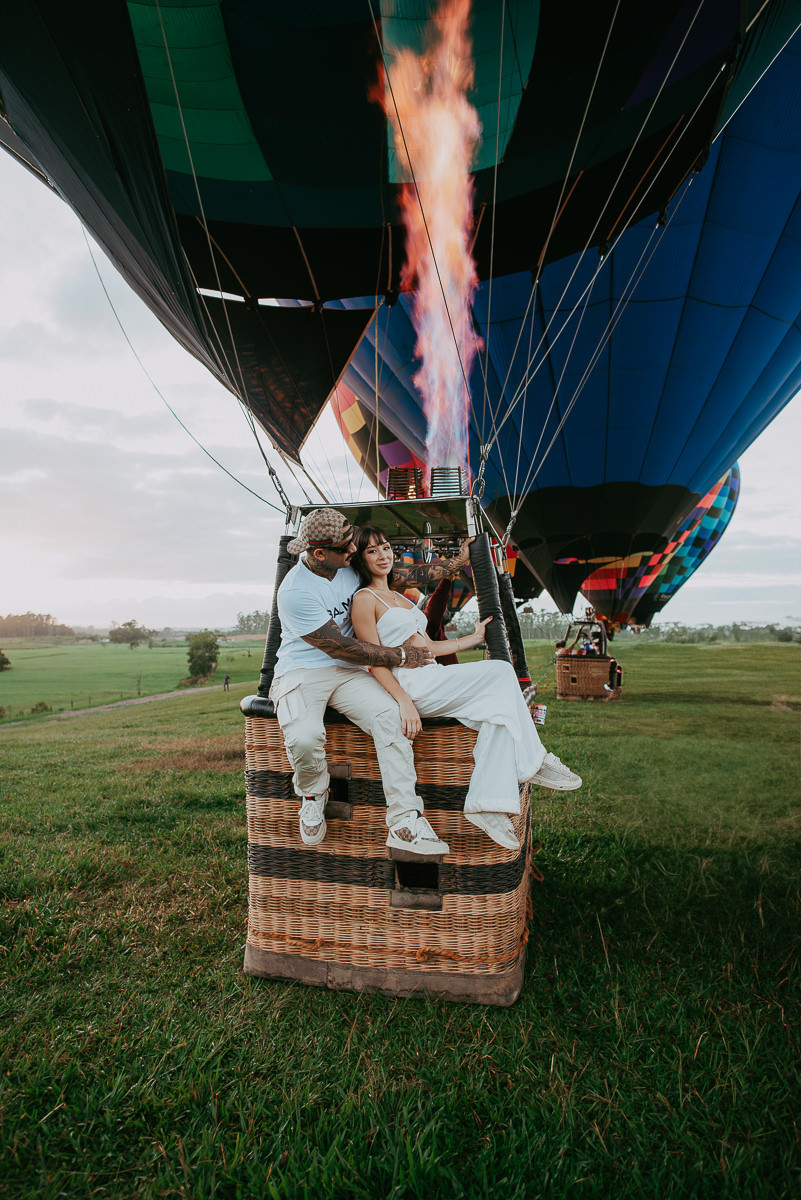 casal sentado na borda do cesto de um balão de ar quente , prestes a voar , durante ensaio fotografico em praia grande sc , com a agencia canyons e peraus, passeio de balão 