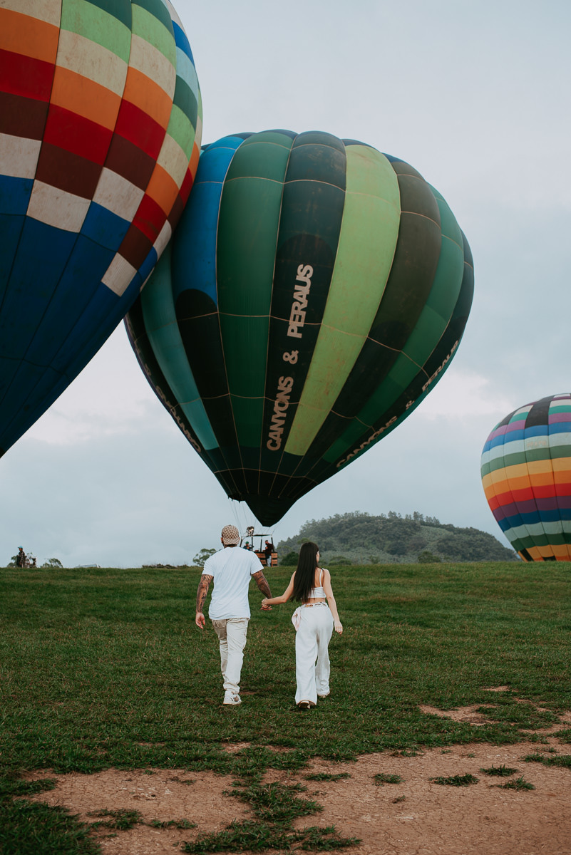 casal indo para o cesto do balão , casal caminhando na decolagem dos balões durante ensaio fotográfico, voo de balão em praia grande SC, com a agencia canyons e peraus 