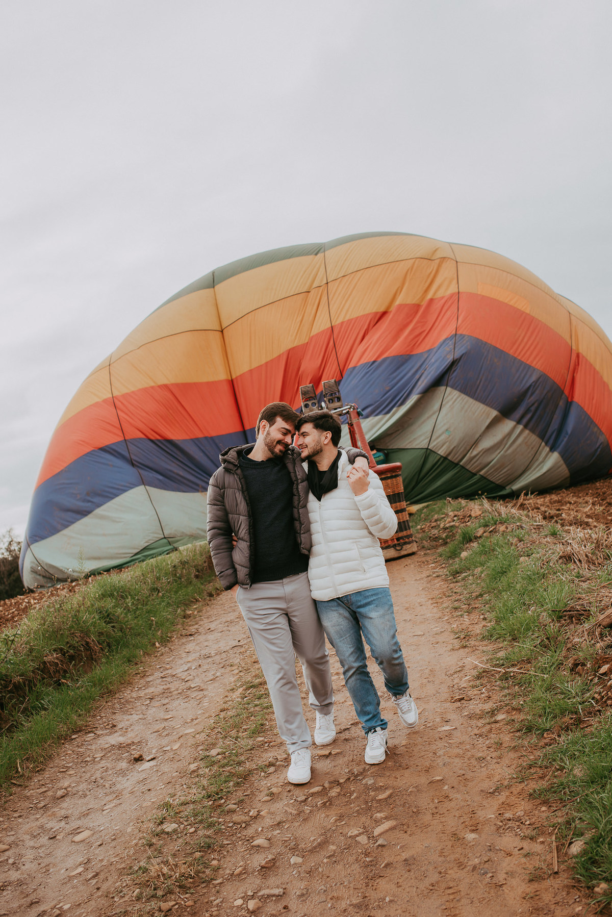 Casal LGBT celebrando pedido de noivado durante passeio de balão.