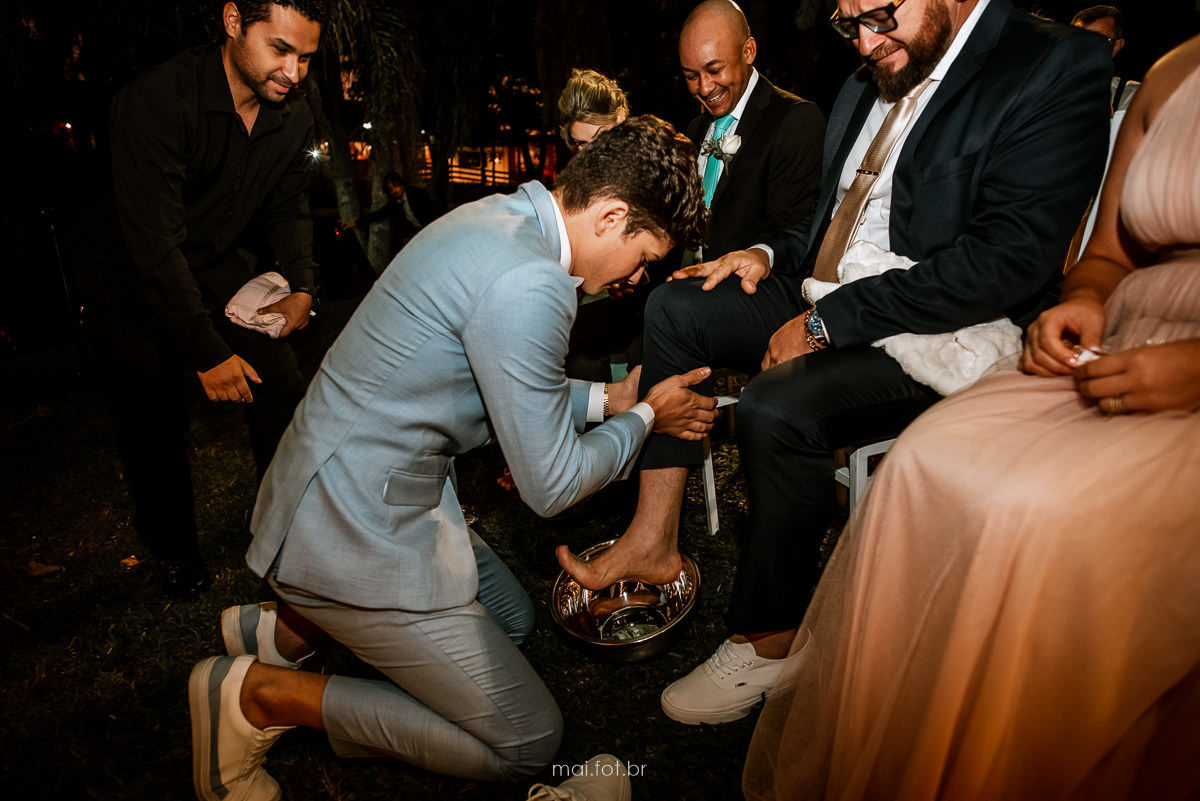 noivo lavando os pés do pai, após a cerimonia de casamento