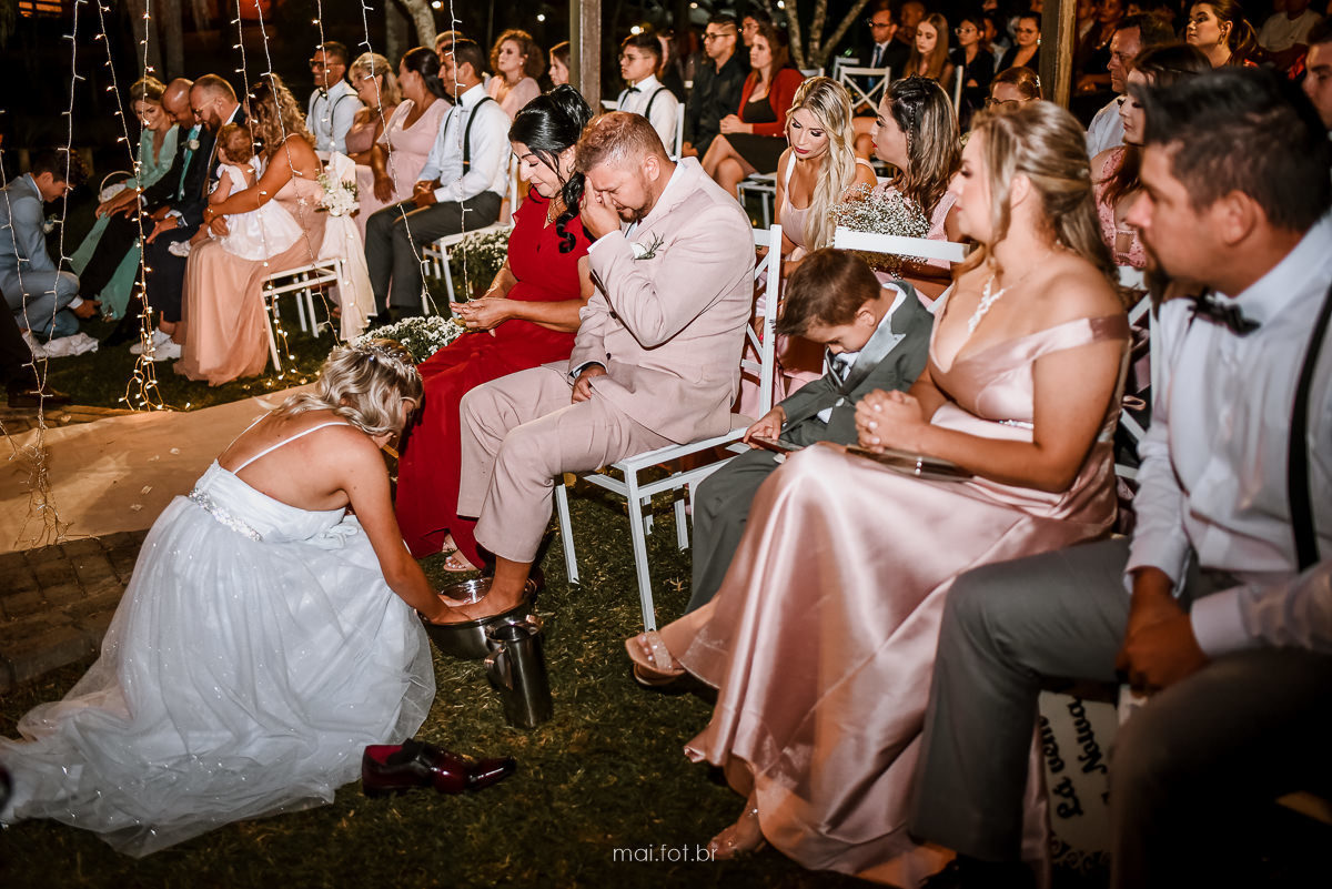 noiva lavando os pés do pai após a cerimonia de casamento 