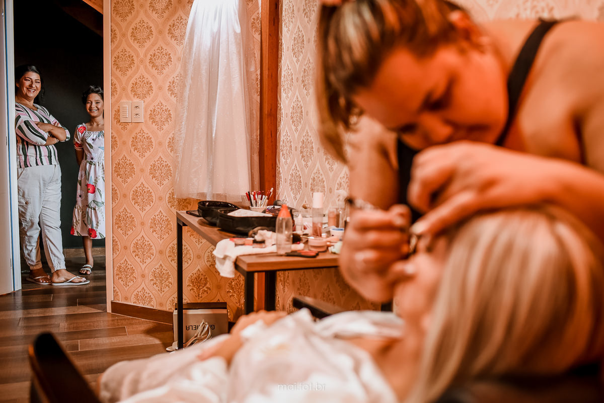 mãe e noivinha espiando a  noiva sendo maquiada no salão de beleza em criciúma 