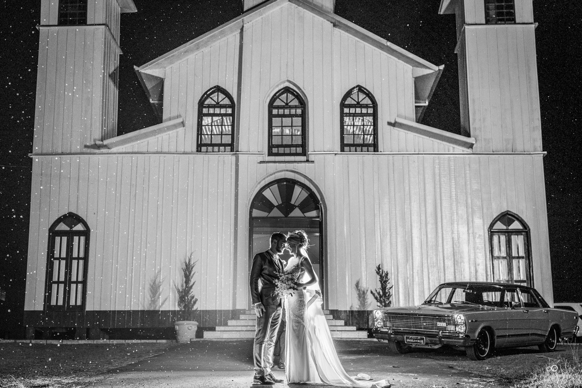 noivos posando em frente a igreja