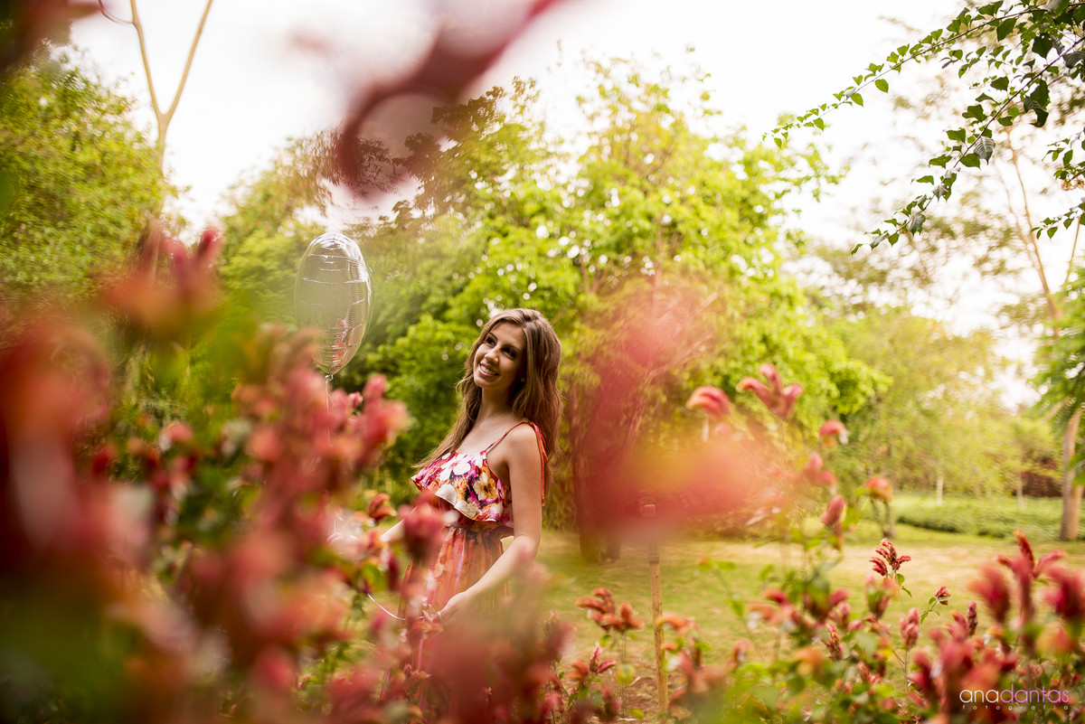 Menina em um campo florido com bexigas de coração 