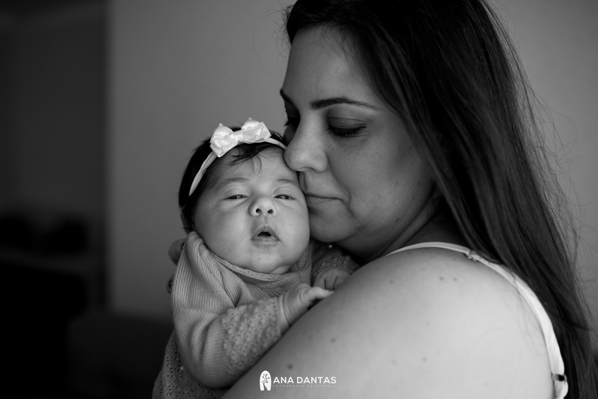 Bebê com os olhos fechados no colo da mãe 