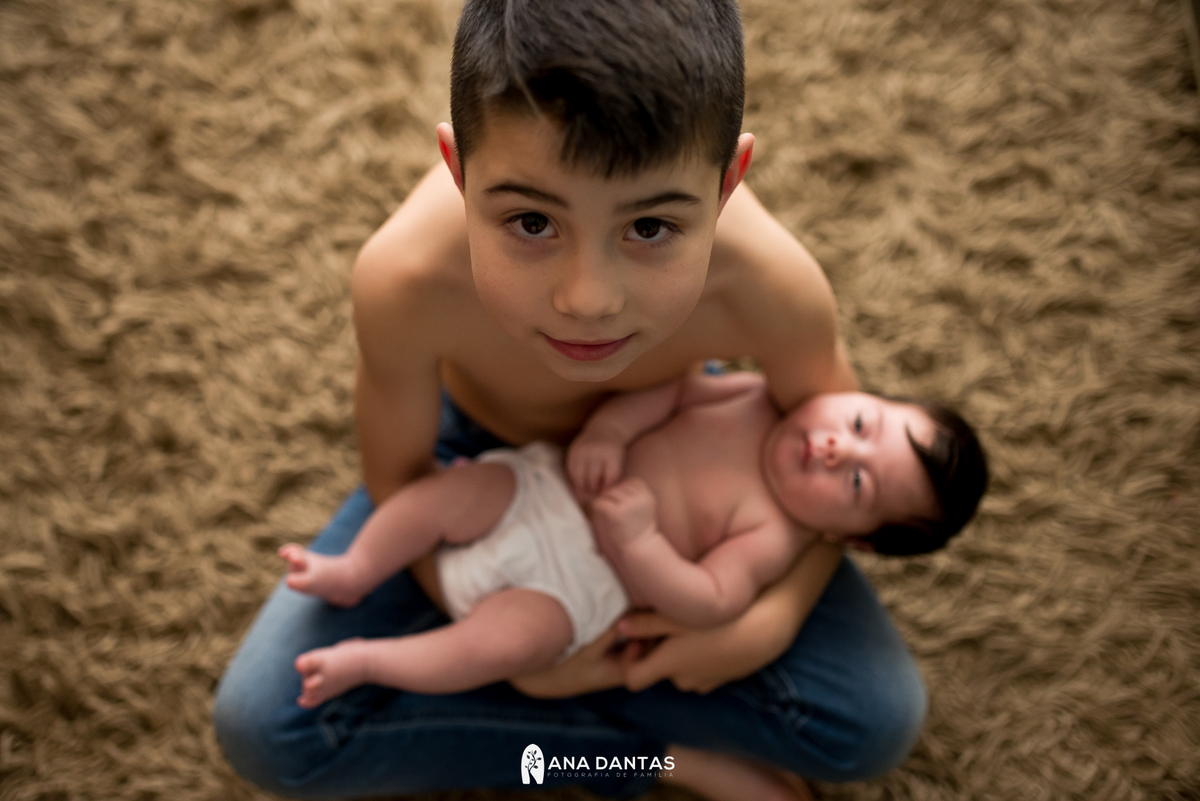 Irmão mais velho segurando sua irmã recém-nascida