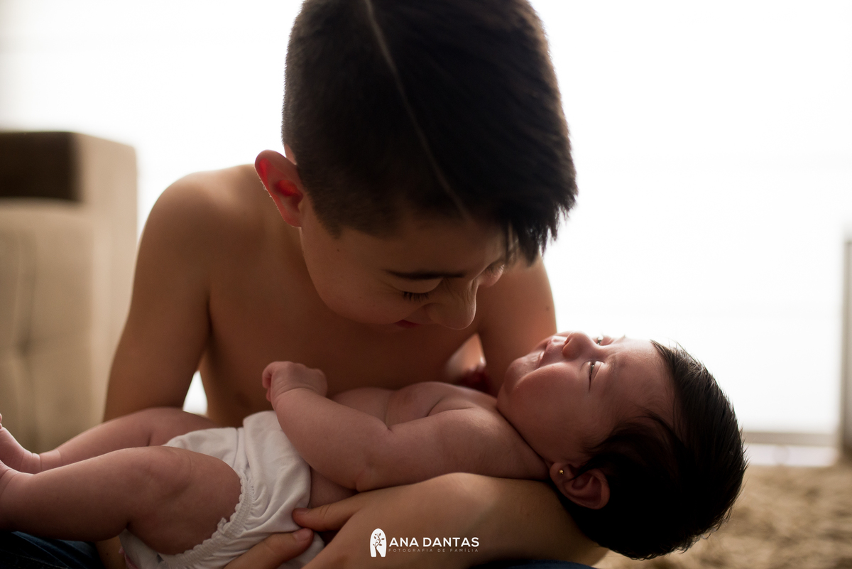 Bebê recém nascido sendo segurado pelo irmão