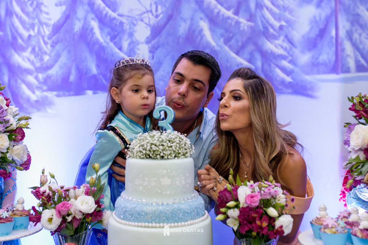 Catarina e seus pais apagando a velinha 