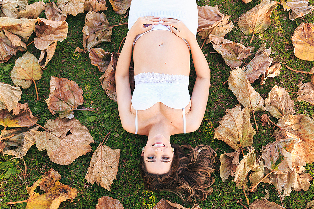 mulher deitada no chao com folhas do lado