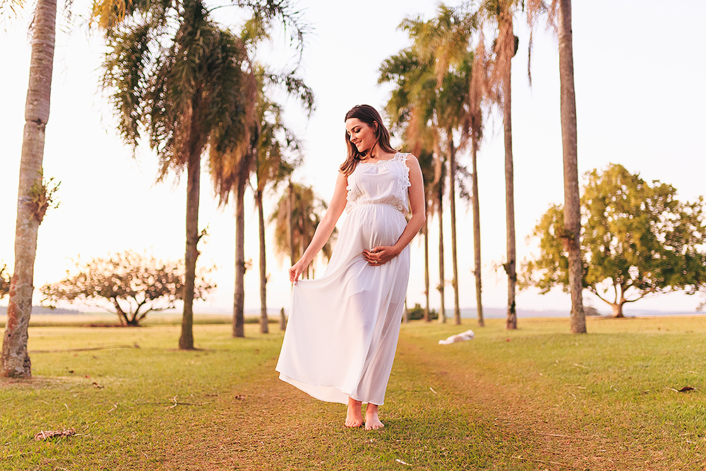 gestante segurando o vestido com os coqueiros ao fundo