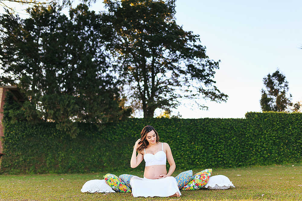 gestante sentada em almofadas com arvore ao fundo
