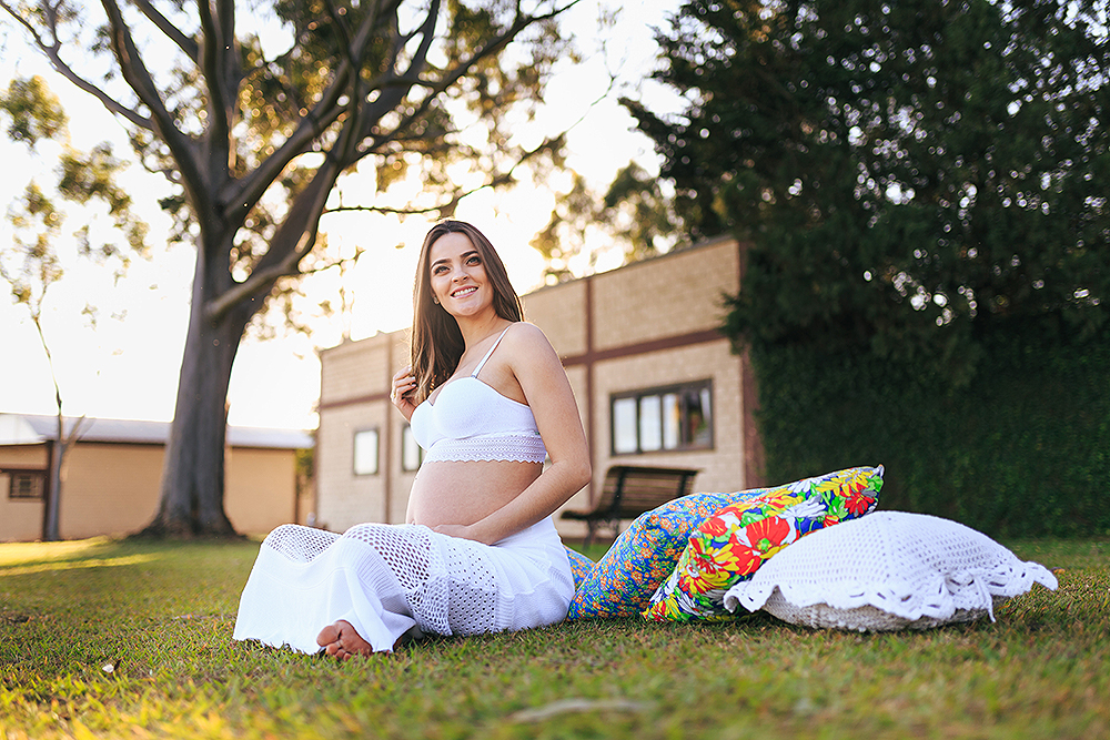 gestante sentada no gramado olhando para o horizonte
