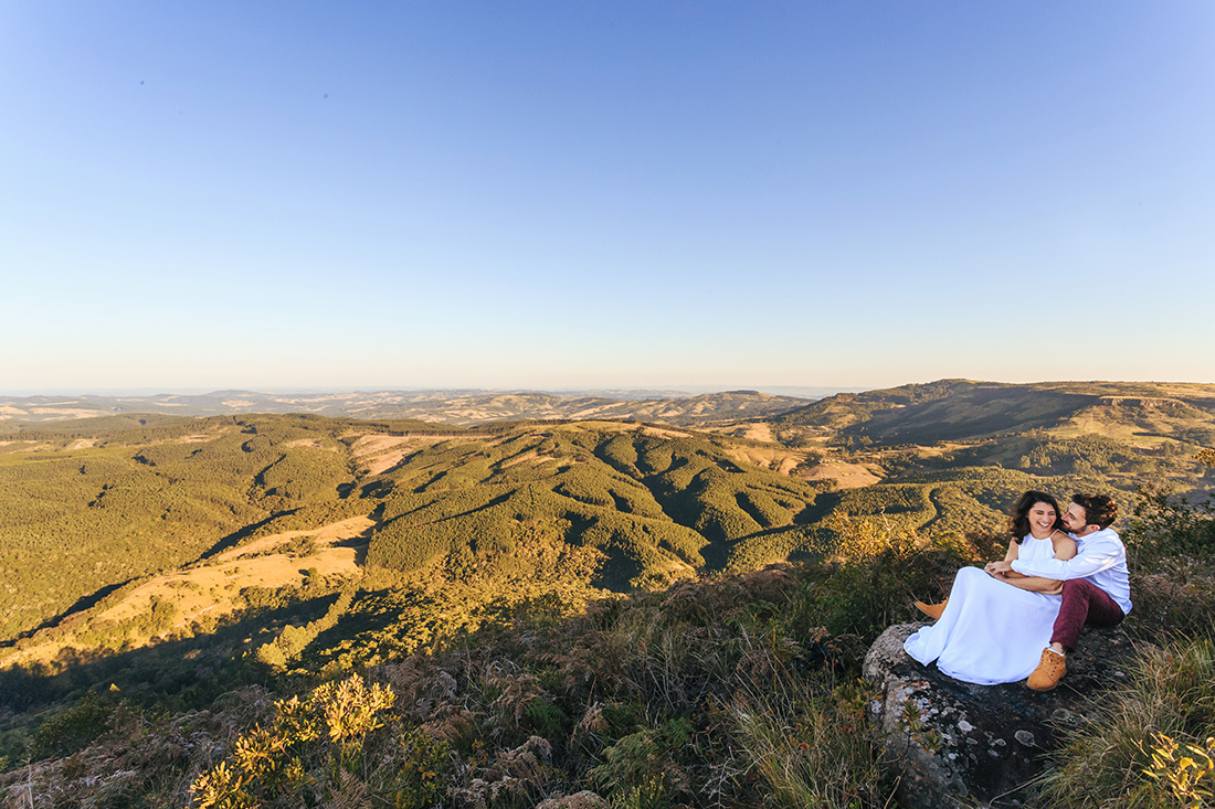 casal sentado no pico de uma montanha namorando