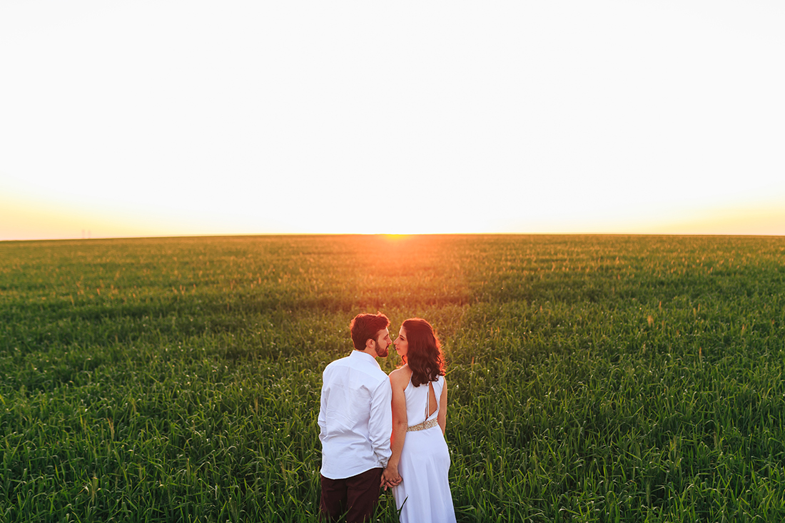 lindo por do sol com o casal de maos dadas dando quase um beijo