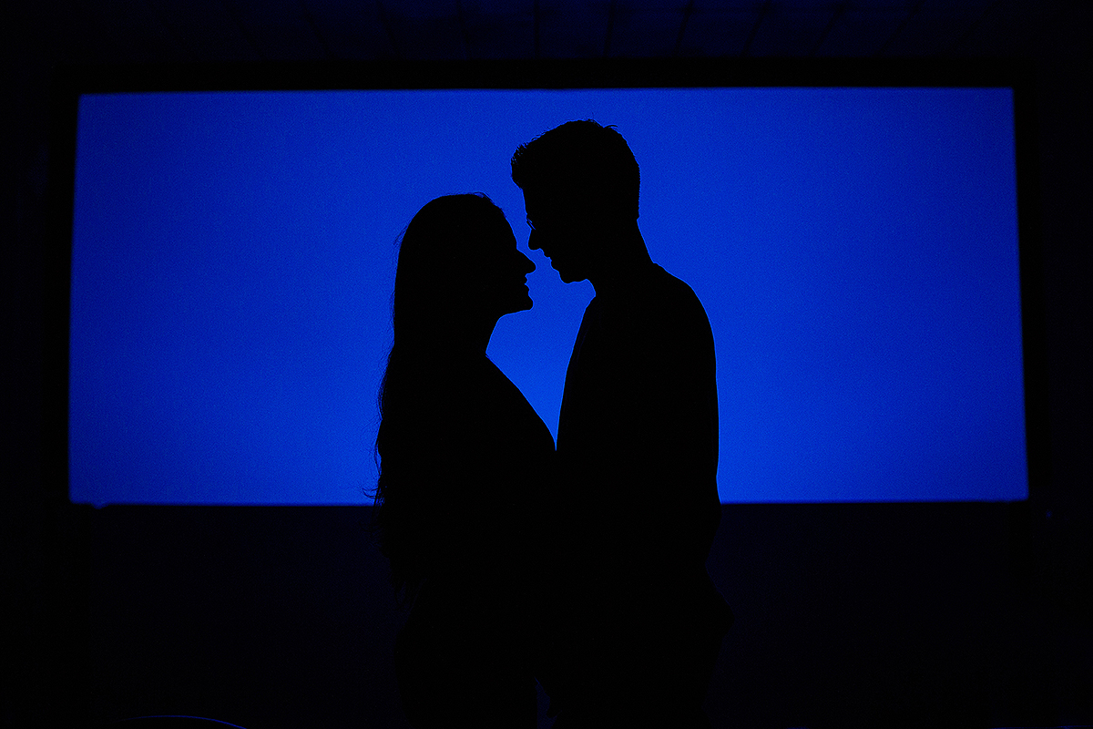 casal olhando um para o outro na frente da tela de cinema