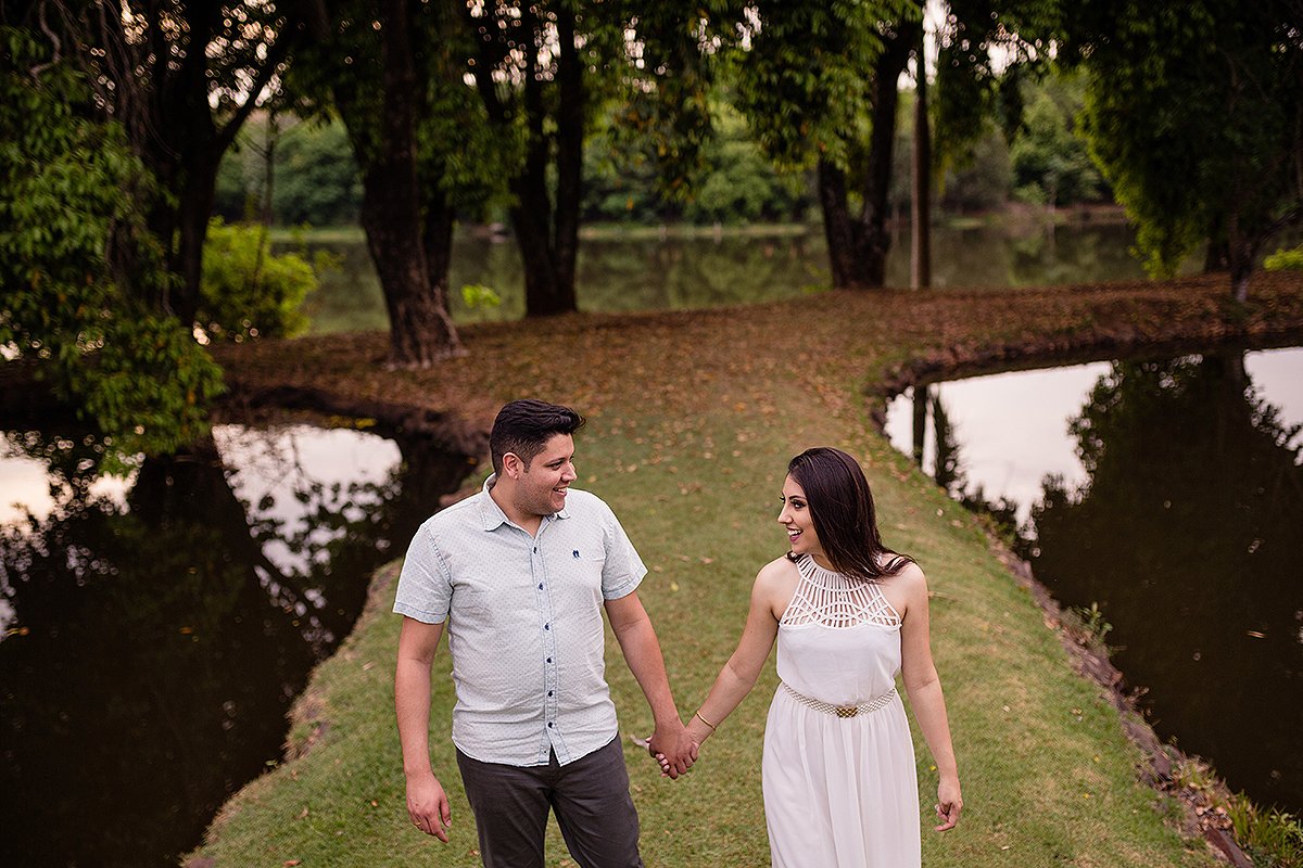 casal andando de mão dadas com lagoa ao lado