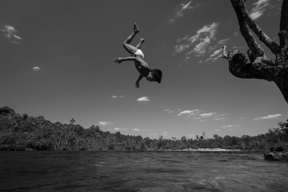 menino pulando de cabeça no rio, na área indígena do oeste do mato grosso na aldeia parecis