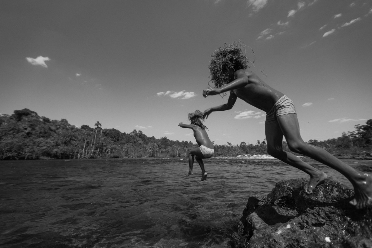 duas crianças pulando da beira do rio na área indígena do oeste do mato grosso na aldeia parecis