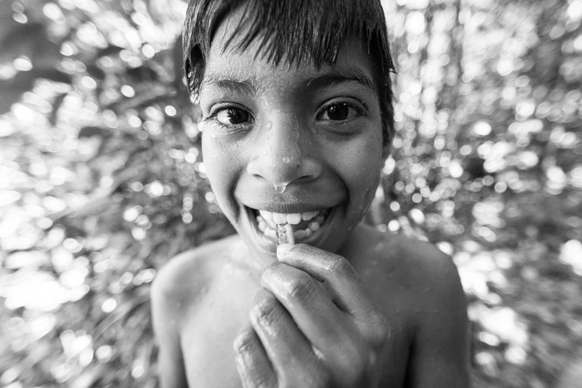 menino índio molhado após banho no rio, com a mão na boca, na área indígena do oeste do mato grosso na aldeia parecis